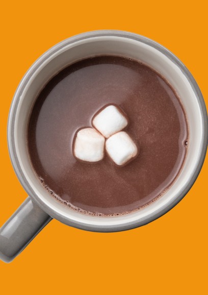 An overhead shot of a mug of hot cocoa against an orange background.