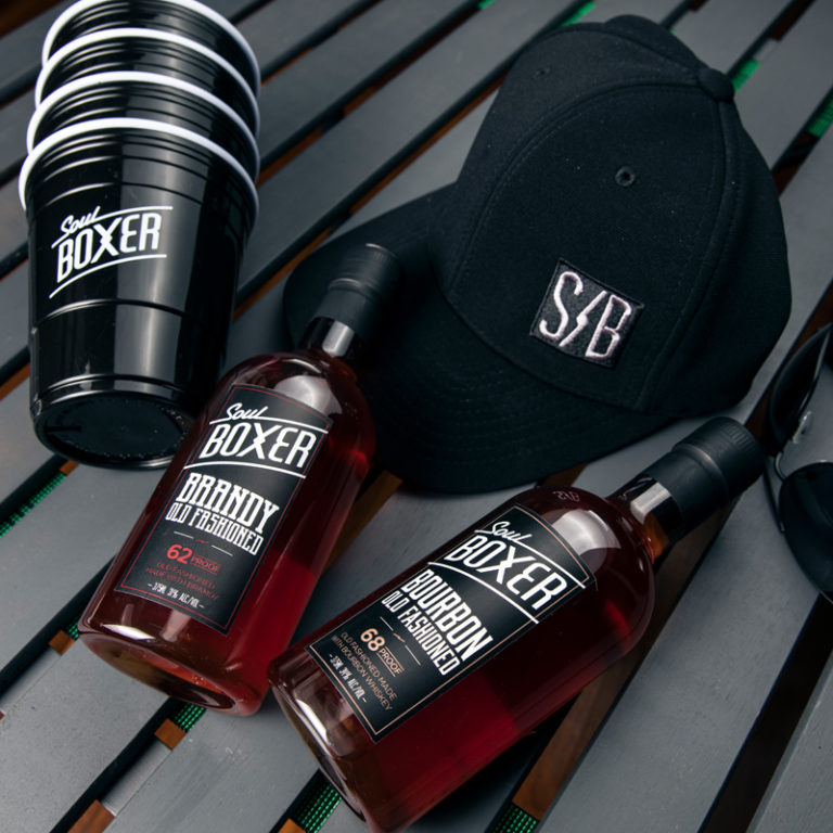 A stack of SoulBoxer solo cups next to a SoulBoxer hat and bottles.