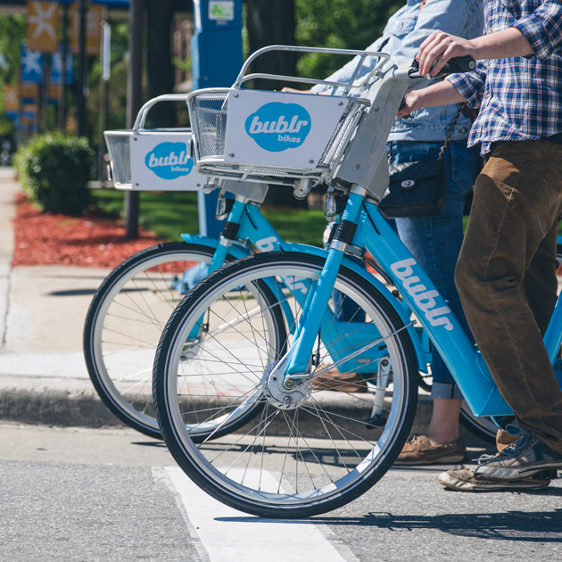 Two bublr bikes stopped on the street.