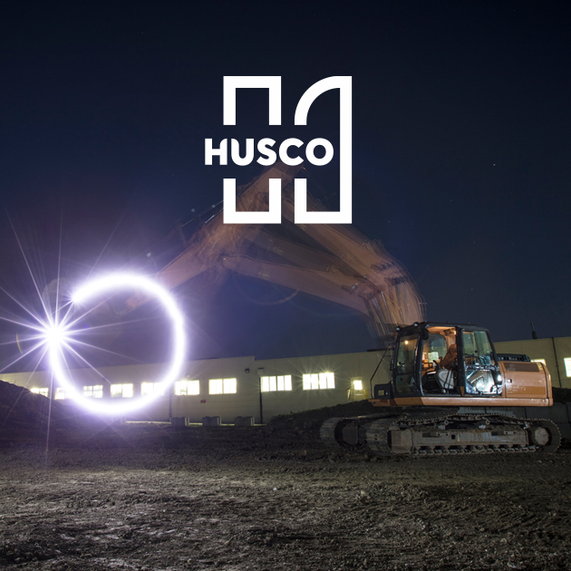A crane on a worksite with the husco logo.