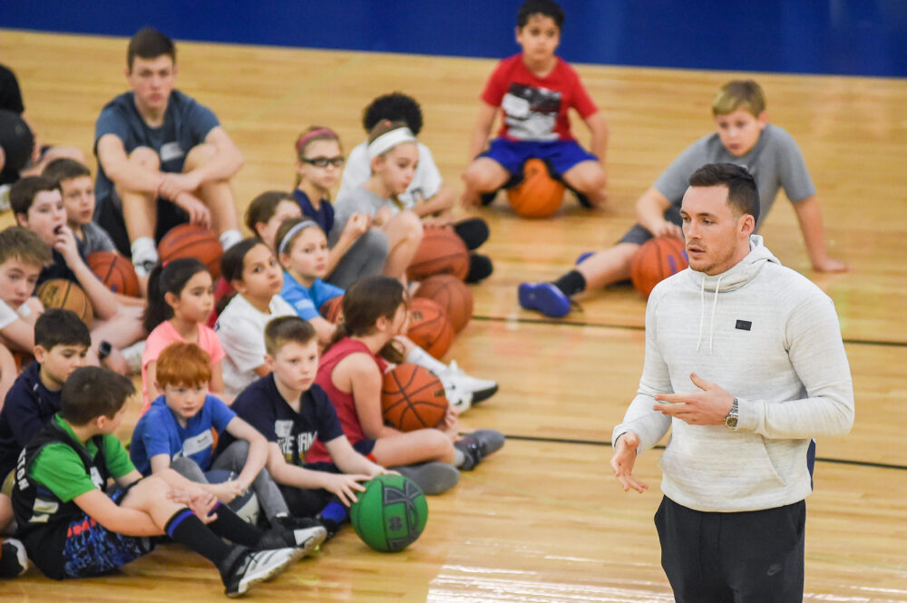 Pat Connaughton talking to a group of kids on a basketball court.