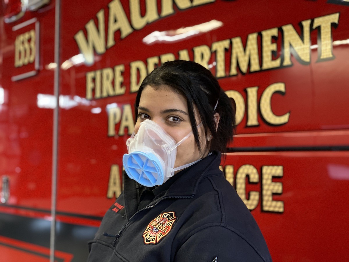 A fire fighter wearing a mask in front of a fire truck.